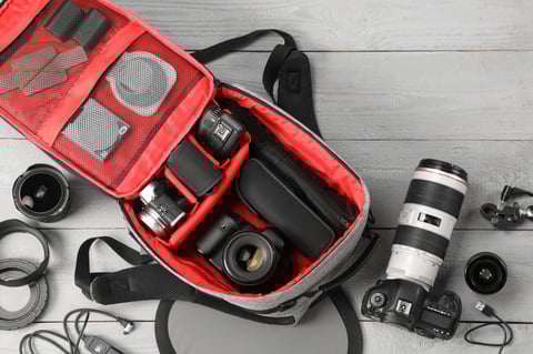 Professional photographer's equipment and backpack on light wooden table, flat lay